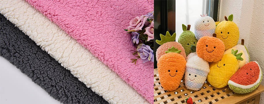 Three rolls of sherpa fleece fabric in black, white, and pink next to plush fruit and vegetable toys with smiling faces.