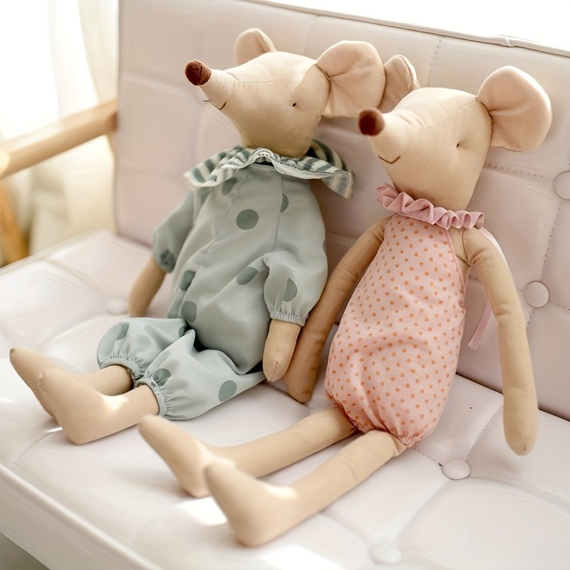 Two soft plush mouse dolls with long limbs, dressed in pastel polka dot outfits, sitting on a white cushioned bench.