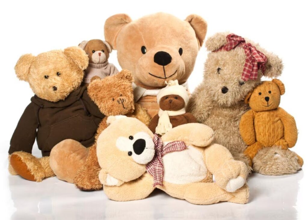 A group of various teddy bears in different sizes, colors, and outfits, arranged closely together against a white background.