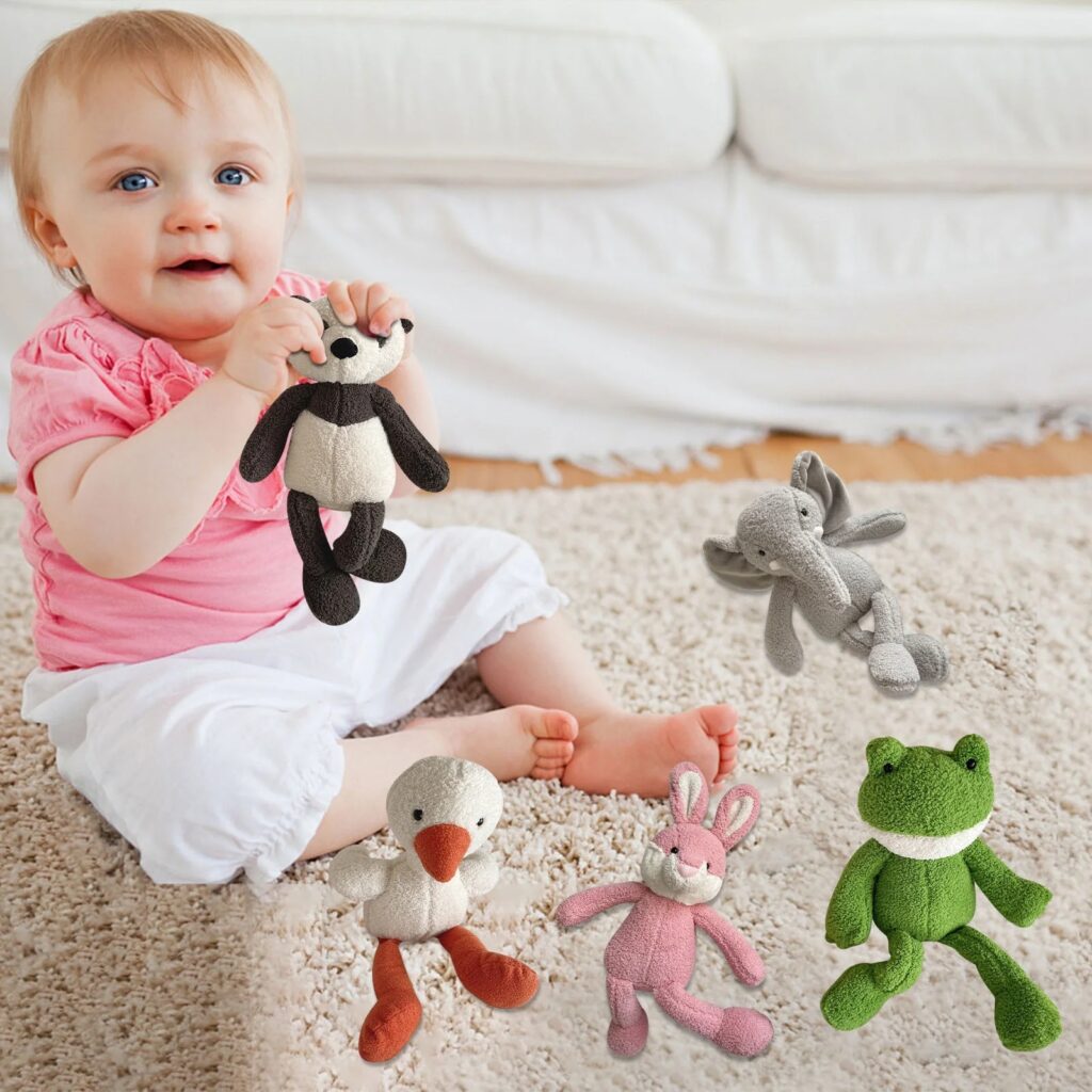 Baby sitting on carpet playing with soft animal plush toys including a panda, elephant, duck, bunny, and frog in various pastel colors.