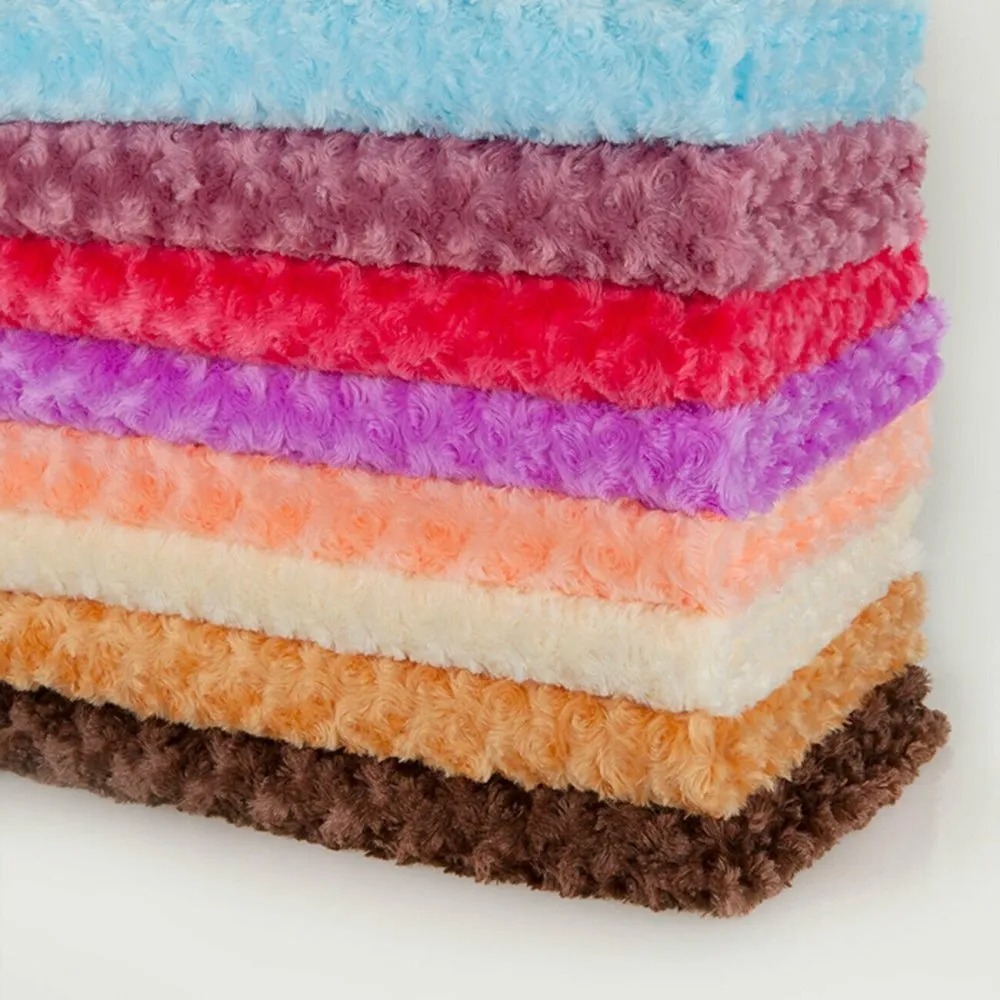 Stack of colorful minky swirl plush fabrics in blue, purple, red, peach, cream, and brown shades, showcasing soft texture.