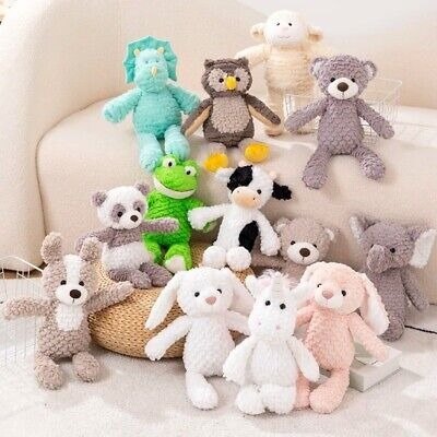 Group of soft plush stuffed animals including bunnies, frogs, bears, cows, and more arranged on a couch and floor.