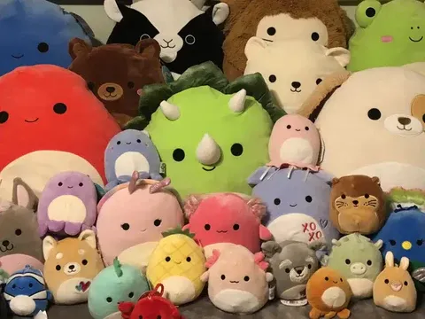 Um grande grupo de brinquedos de peluche coloridos e com formas únicas, dispostos em conjunto, incluindo animais, frutos e personagens de fantasia.
