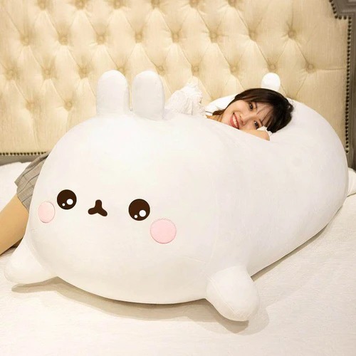 Girl lying on oversized white bunny plush toy with cute pink cheeks and tiny ears.