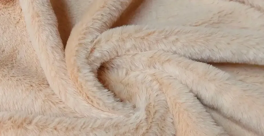 Textura de tecido de pelúcia bege em espiral, mostrada em grande plano, realçando a sua suavidade e superfície semelhante a pelo.