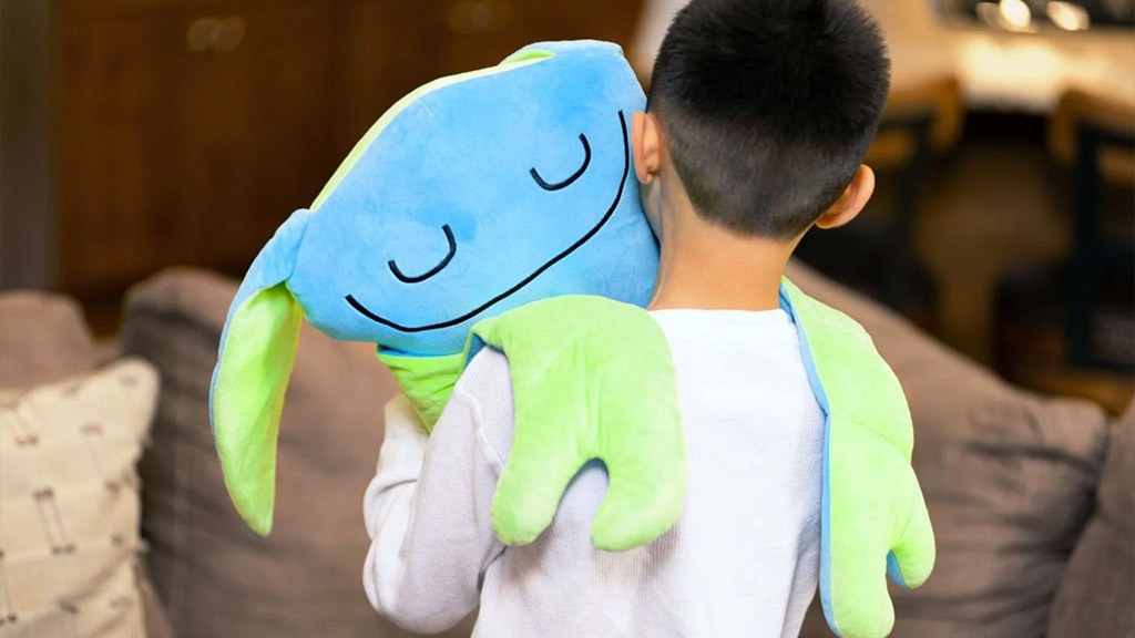 Boy cuddling soft blue and green frog plush pillow