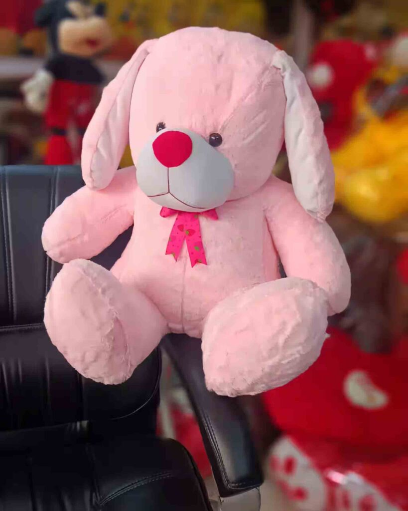 Soft pink plush dog with red nose and bow