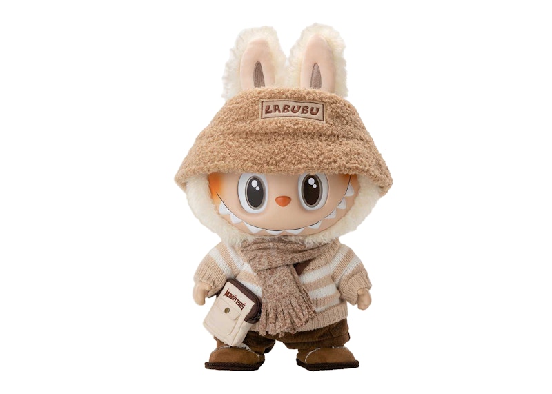 Cute Labubu plush doll wearing a beige hat, scarf, and striped sweater with a small bag.