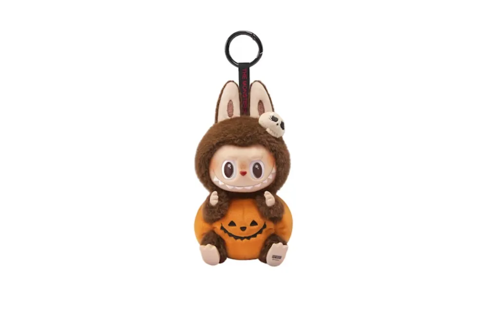 Small plush keyring dressed in brown Halloween costume with pumpkin design and skull detail.