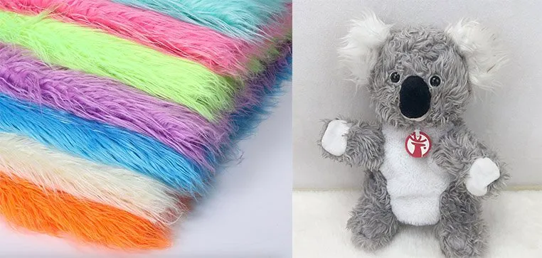 Stack of vibrant faux fur fabrics next to a grey and white plush koala toy