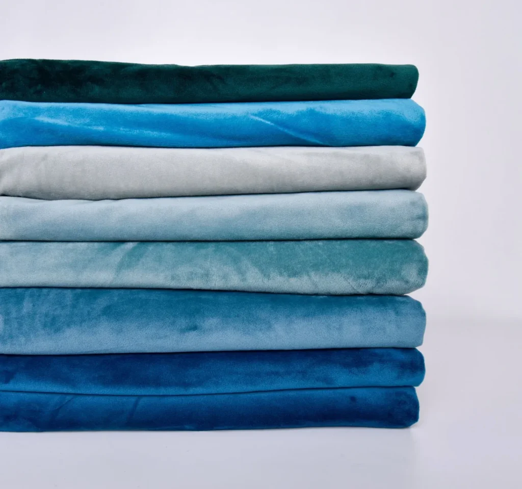 Stack of soft fabrics in various shades of blue and green, neatly folded
