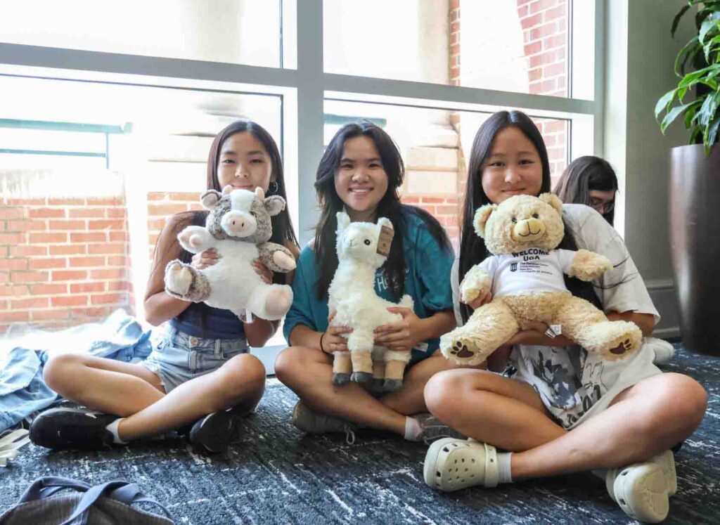 Three girls holding stuffed animals indoors