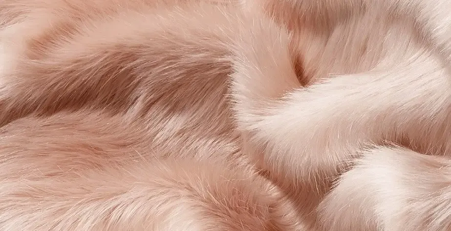 Grande plano pormenorizado de um luxuoso e macio tecido de peles artificiais cor-de-rosa com uma textura sedosa e padrões ondulados de aspeto natural.