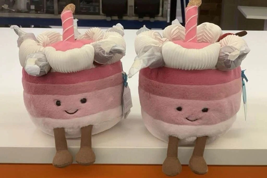 Two smiling pink and white plush cake toys with legs
