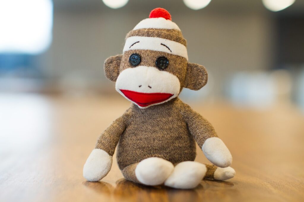 Peluche scimmia con cappello rosso seduto sul tavolo