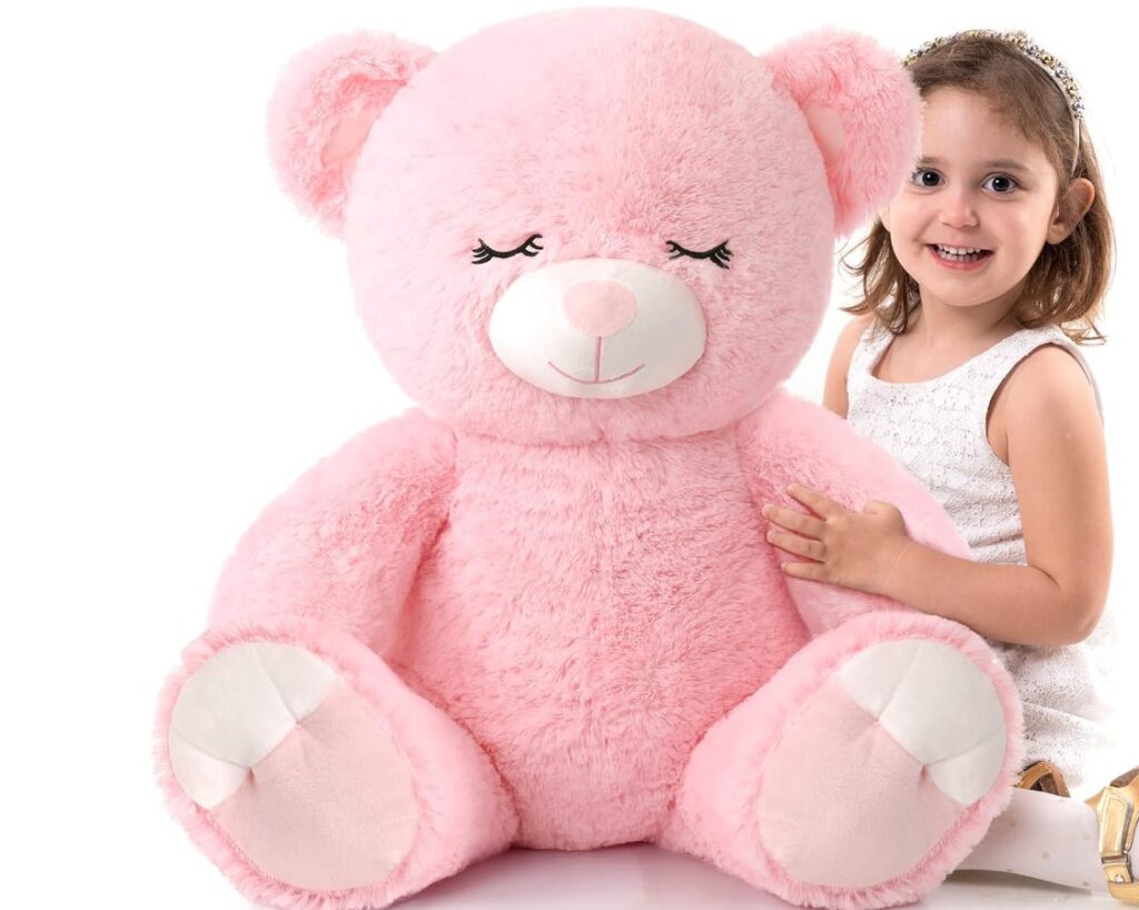 Little girl smiling with huge pink teddy bear plush toy