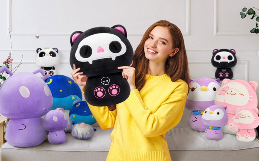 Una donna con un maglione giallo che tiene in mano un peluche di gatto nero con il disegno di un teschio, circondata da peluche colorati e simpatici in stile cartone animato, tra cui funghi, animali e panda su un divano.