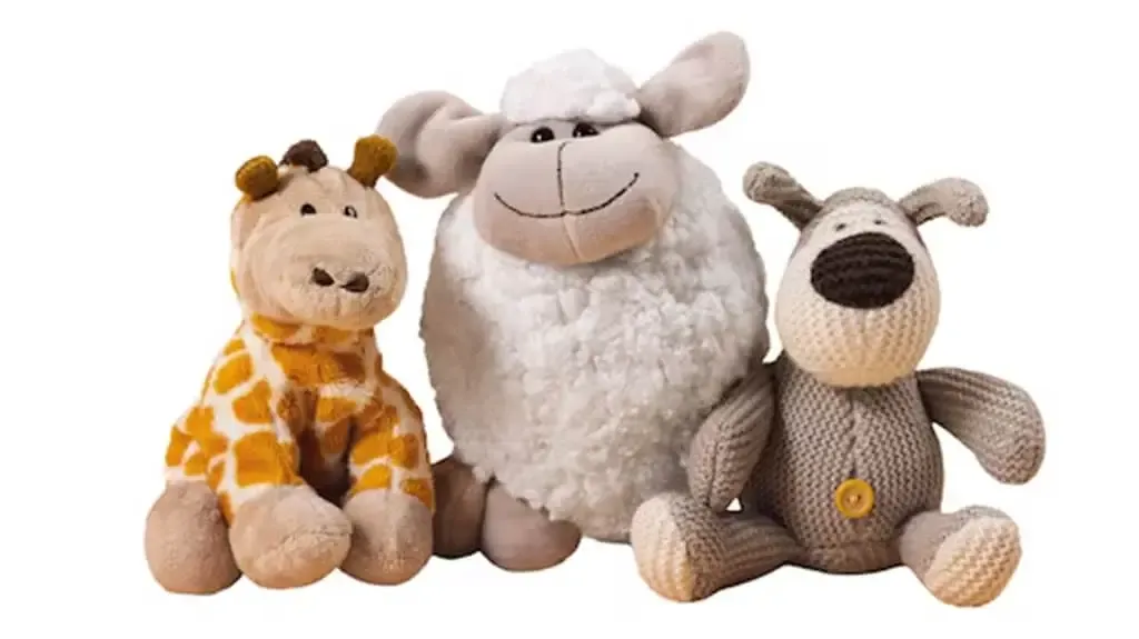 Giraffe, sheep, and dog plush toys sitting together on white background.