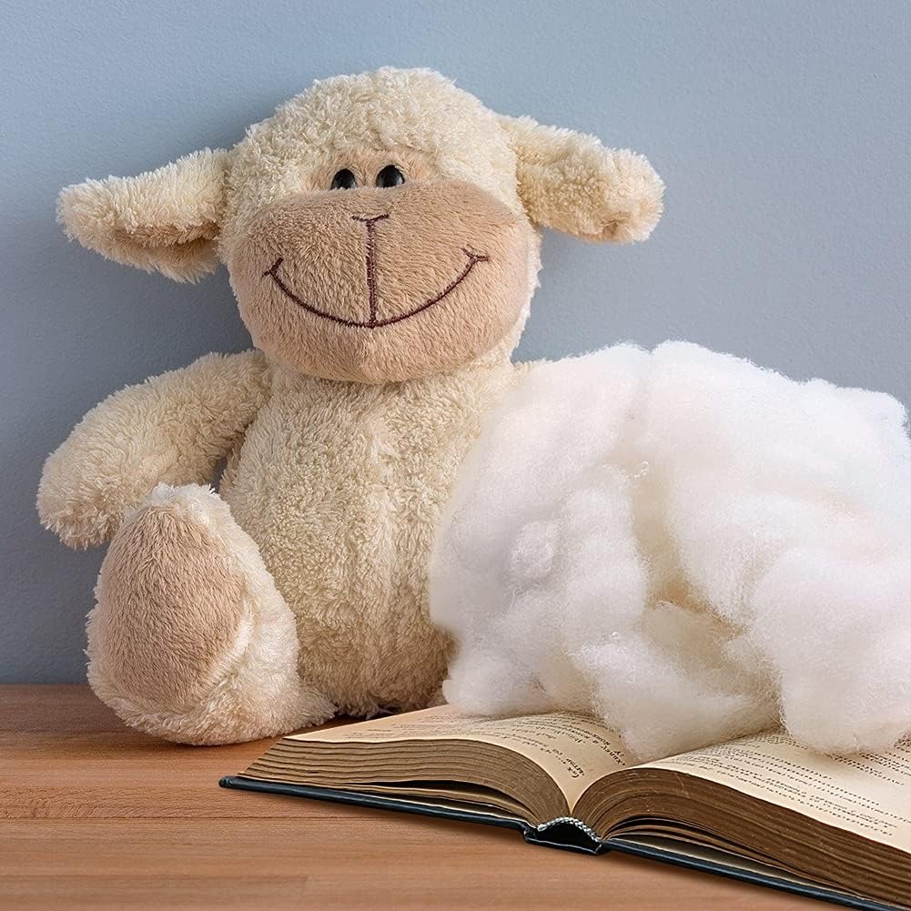 Pluizig beige gevuld lammetje naast polyester fiberfill en een open boek op een houten tafel