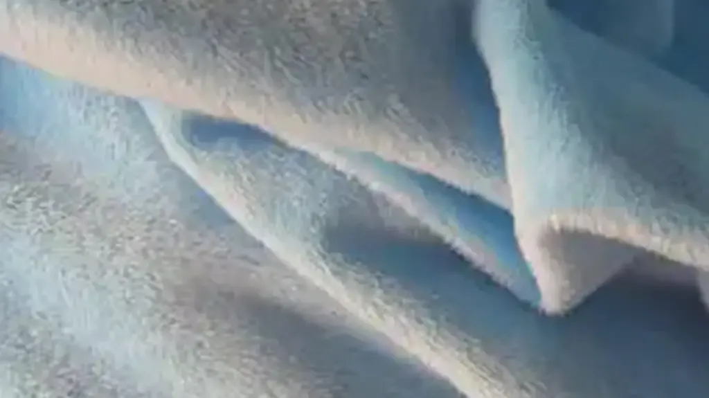 Grande plano de um tecido de pelúcia azul claro, mostrando a sua textura macia e felpuda, ideal para peluches.