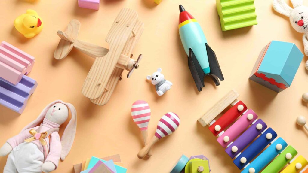 Layout piatto di giocattoli per bambini colorati su sfondo color pesca