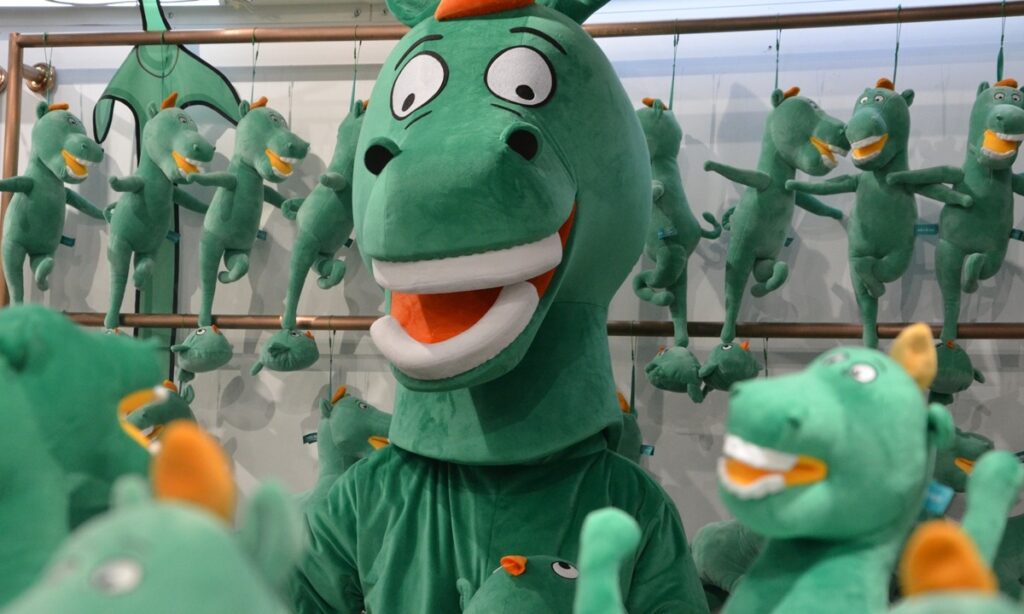 Large green dragon mascot surrounded by smaller green dragon plush toys