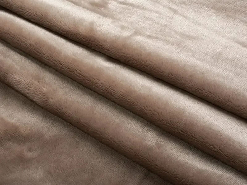 Camadas dobradas de tecido de pelúcia curto castanho com uma textura suave e macia.