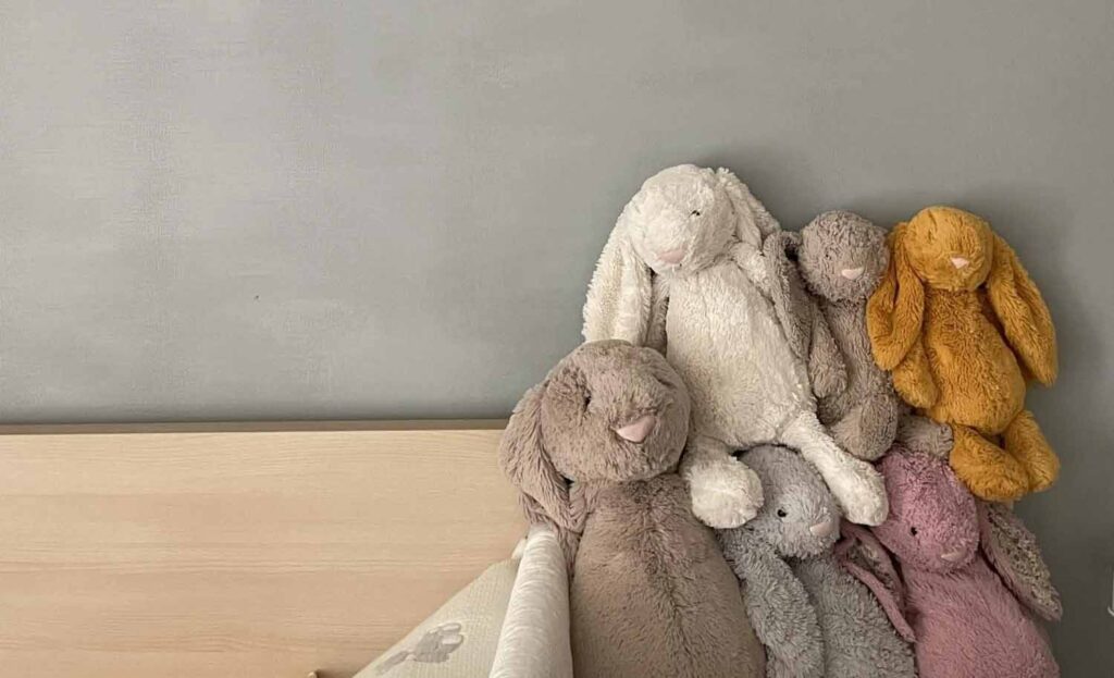 Soft stuffed bunny toys in pastel colors on a bed