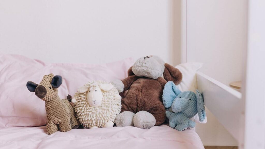 Various plush toys on a pink bedspread