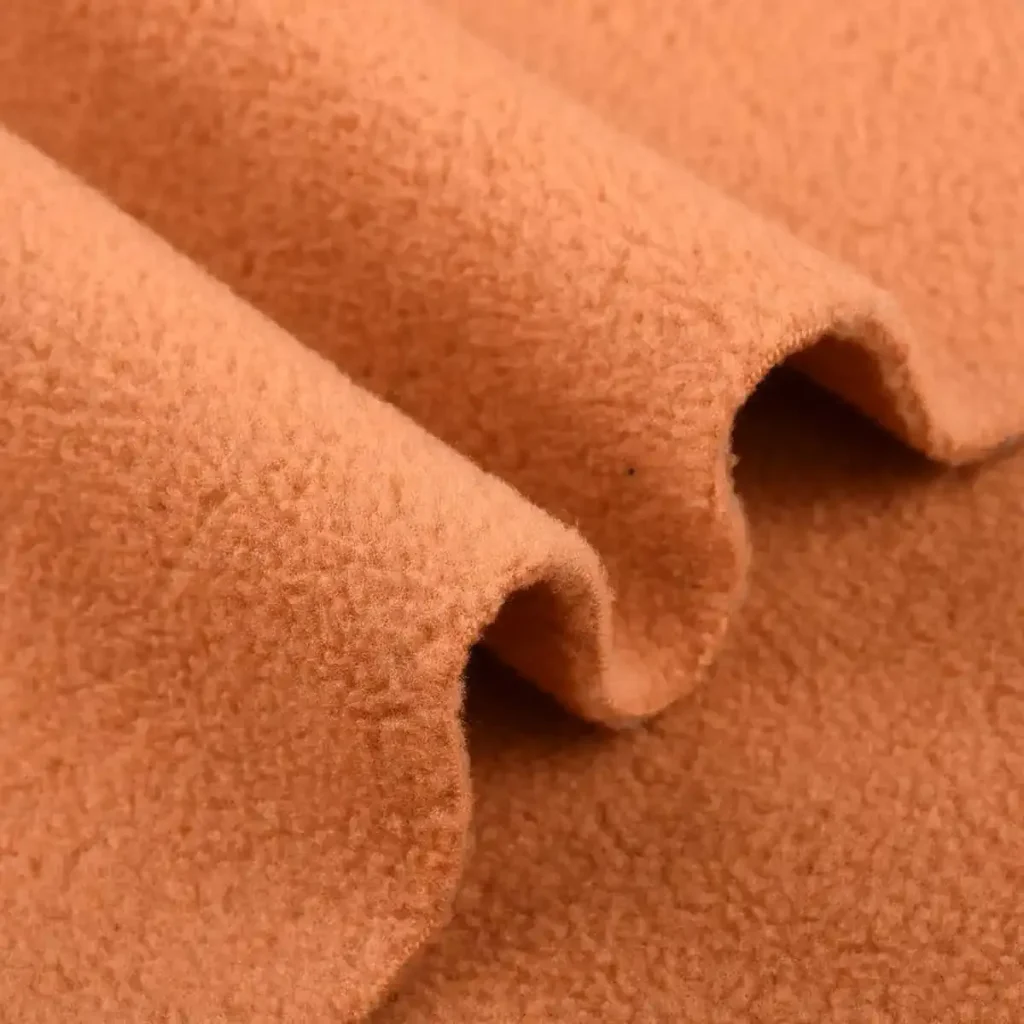 Soft orange polar fleece fabric with textured surface and wavy folds