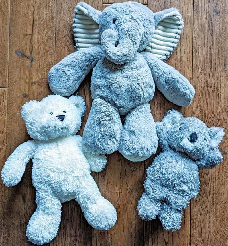 Blue elephant, white bear, and gray koala plush toys on wooden floor.