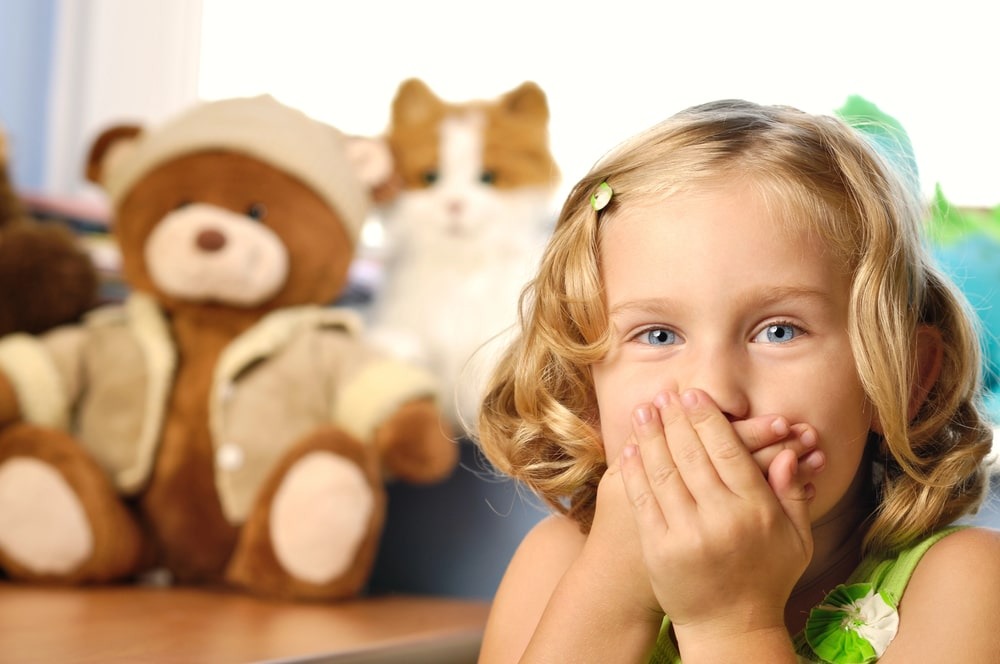 Young girl smiling with plush toys in background