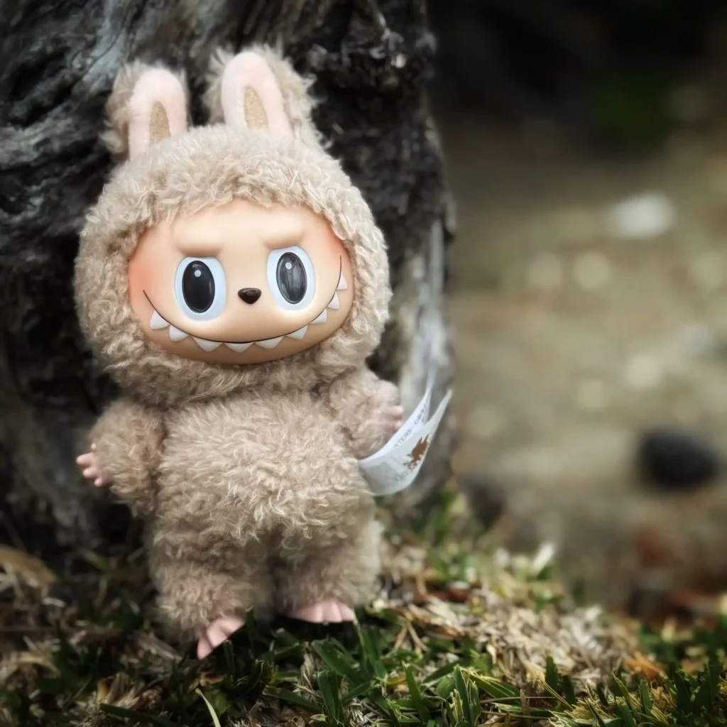 Labubu monster plush toy outdoors near tree.