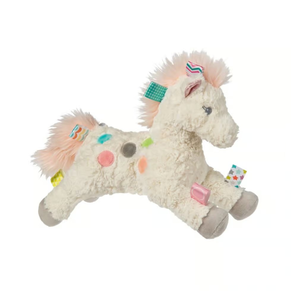 Cream-colored plush pony toy with pink mane, colorful tags, and textured patches designed for sensory play.