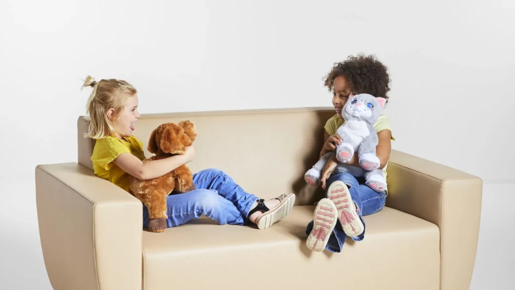 Two children playing with stuffed dog and cat toys on sofa