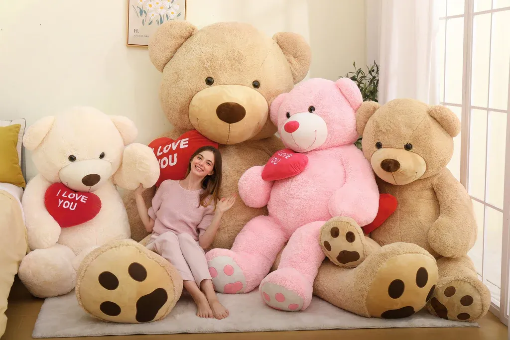 Woman sitting happily among four large teddy bears holding red "I love you" hearts.