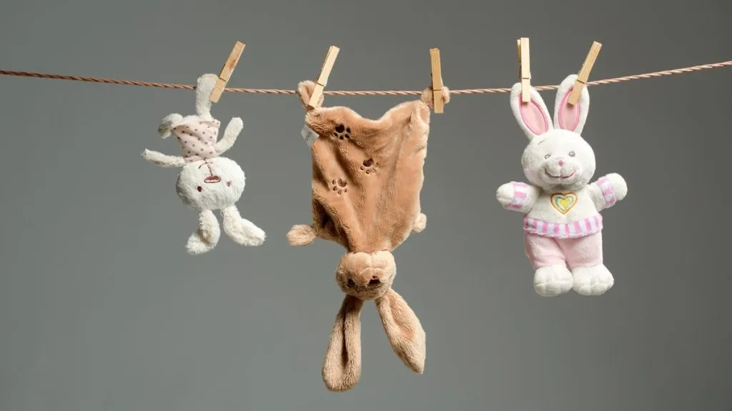 Three plush toys drying on clothesline with clothespins