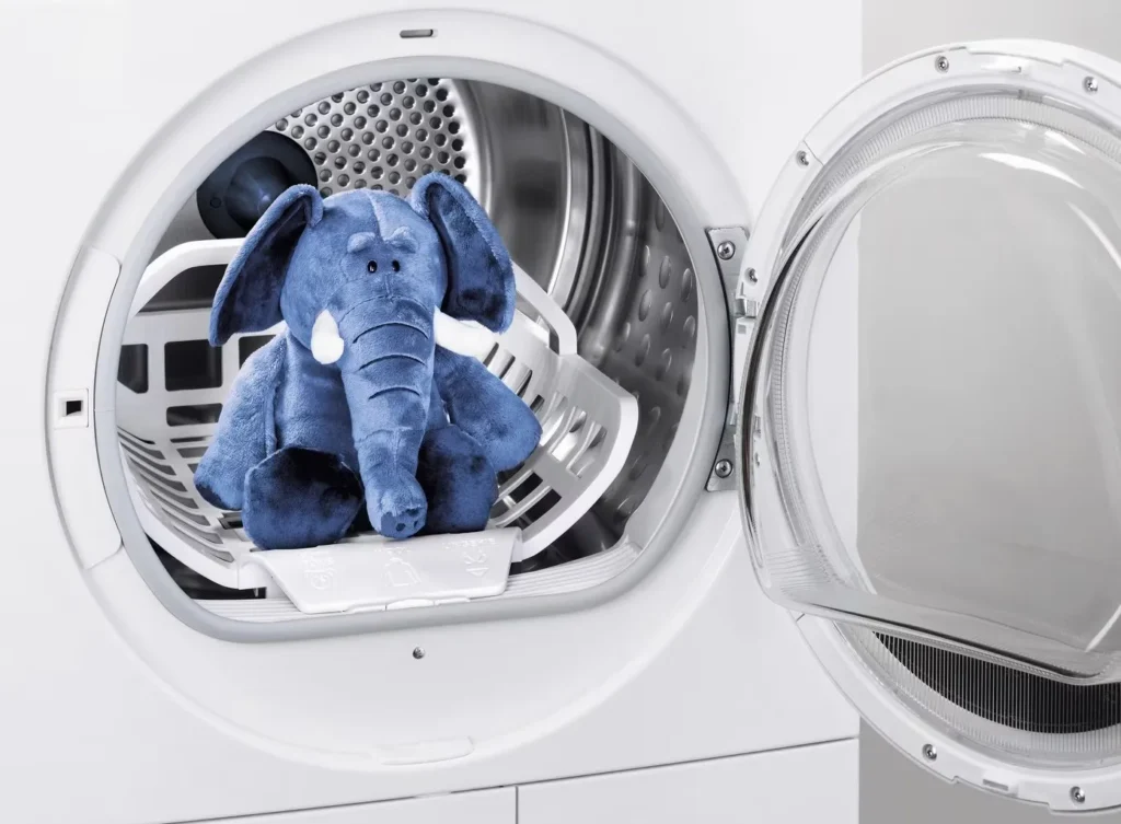 Plush elephant toy inside a dryer machine door open