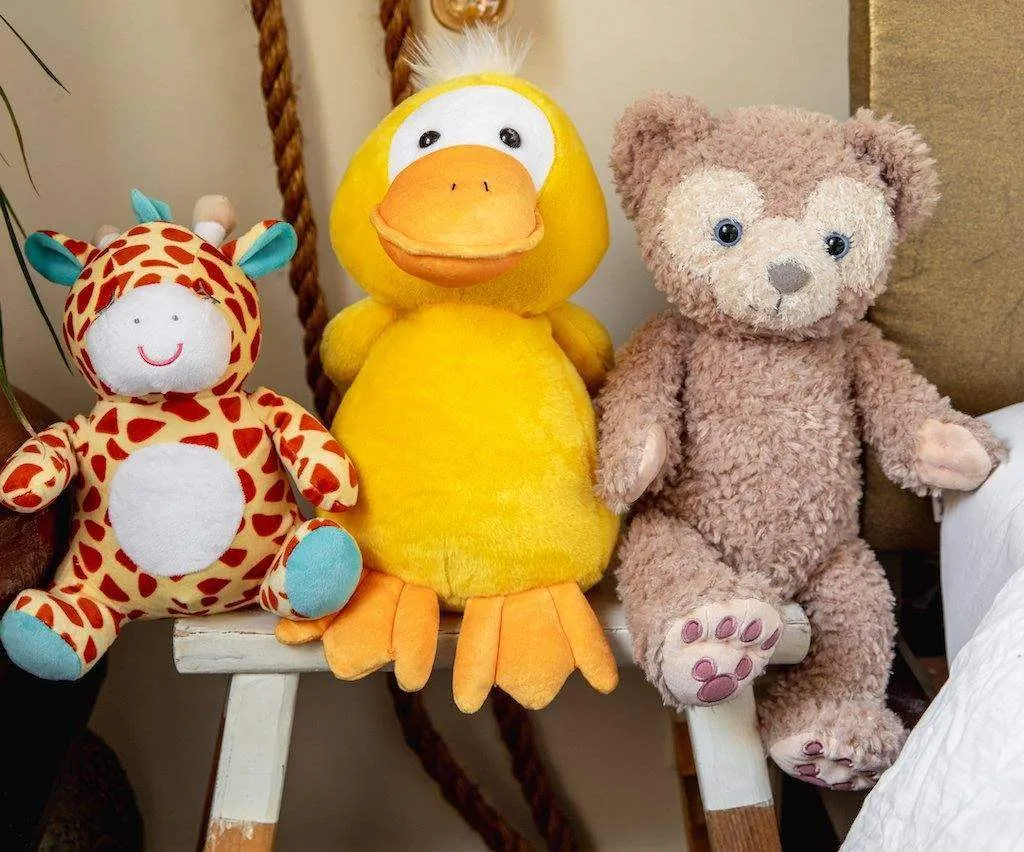 Giraffe, duck, and bear stuffed animals sitting on wooden bench