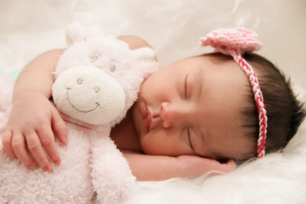 Sleeping baby hugging soft pink plush toy peacefully