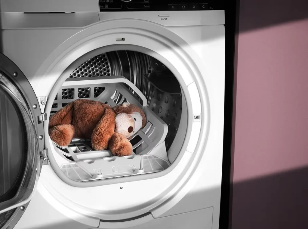 Brown teddy bear inside dryer machine door open