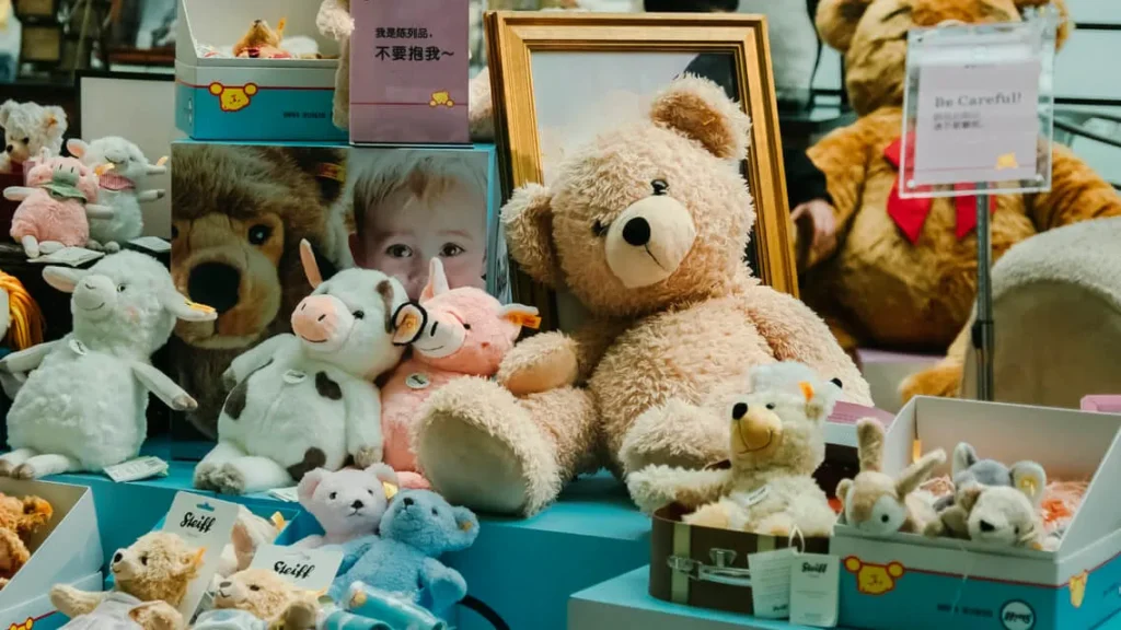 Assorted plush animals and teddy bears displayed on a store counter with signage.