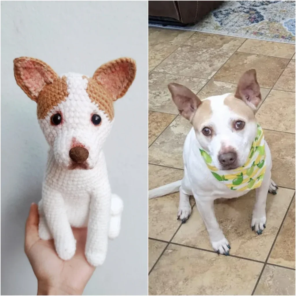 Hand holding crocheted dog resembling real dog sitting on tiled floor with bandana.