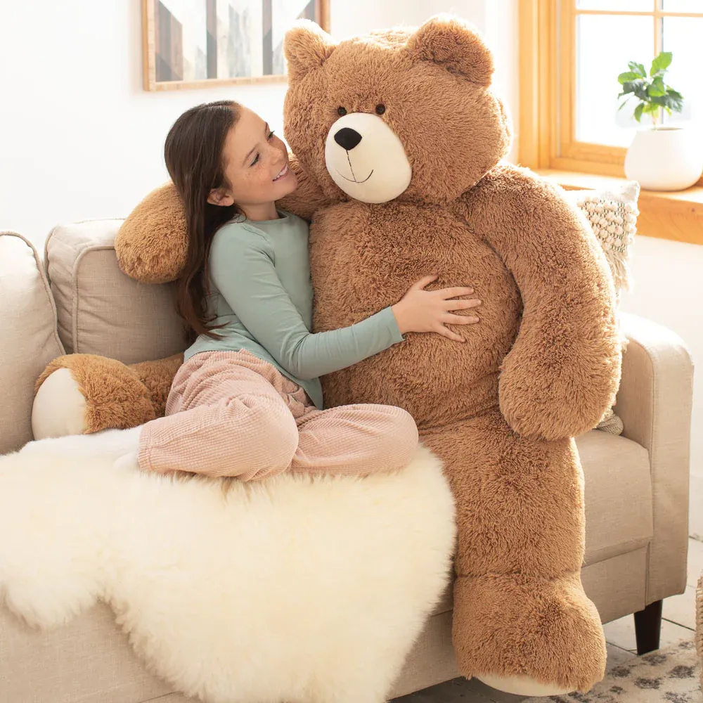 Girl hugging big brown teddy bear on couch