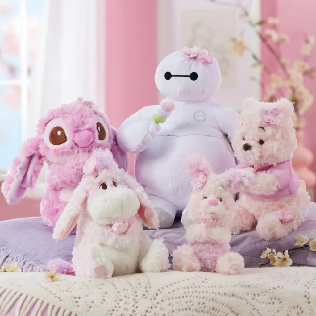 Five plush toys including a white robot and various pink stuffed animals with flowers.