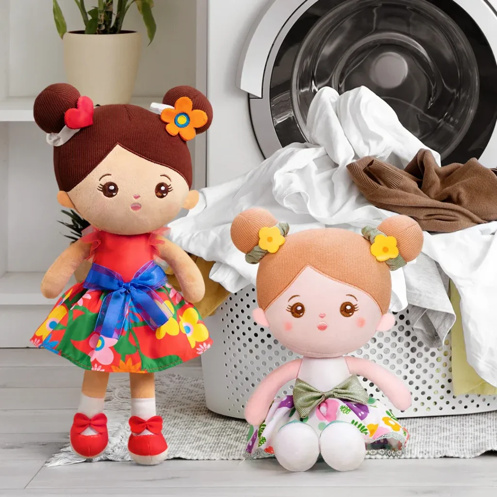 Two colorful dolls sitting by a laundry basket filled with clothes.