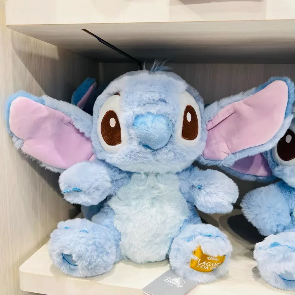 Soft blue Stitch plush toy with big ears sitting on a shelf.