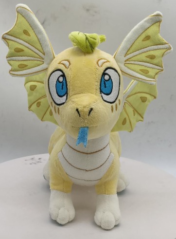 Front view of yellow plush dragon with large blue eyes, blue tongue, and patterned wings.
