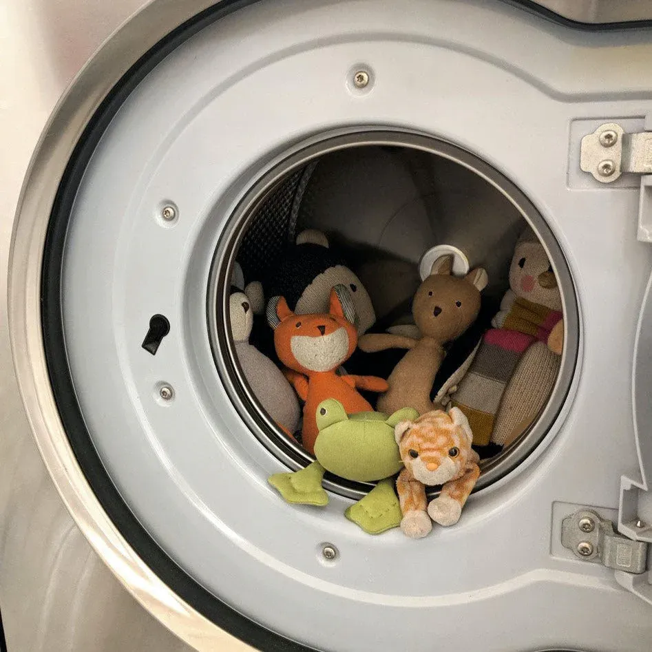 Multiple stuffed animals inside a front-loading washing machine.
