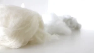 White wool and synthetic stuffing fibers on white background.